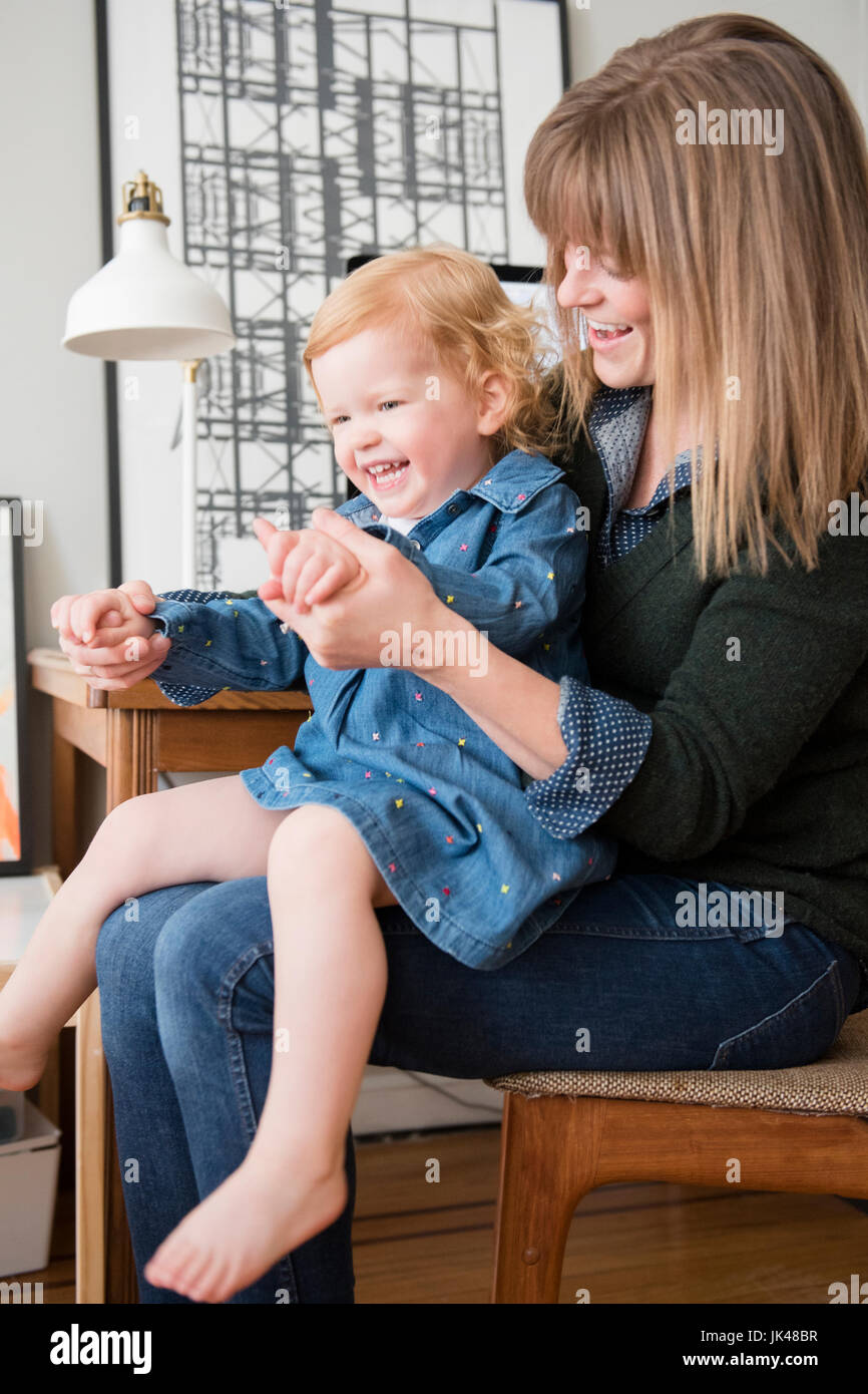 Caucasian mother playing with daughter sitting in lap Stock Photo Alamy