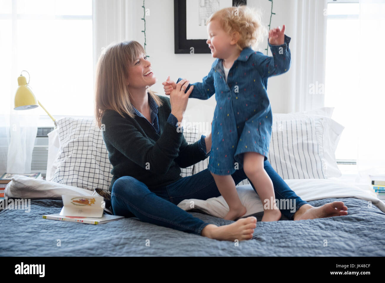 Caucasian mother sitting on bed playing with daughter Stock Photo