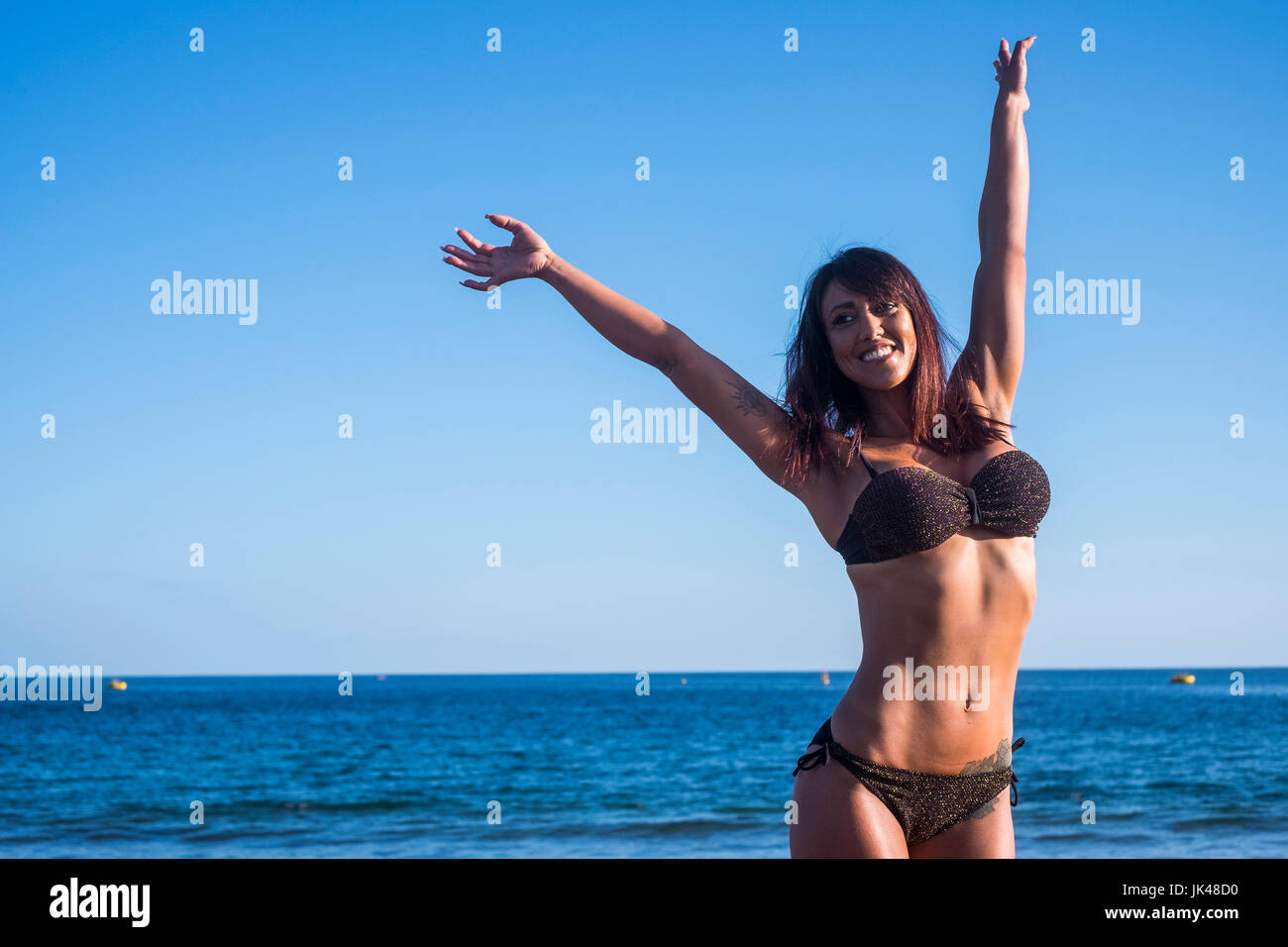 Caucasian woman celebrating on beach Stock Photo