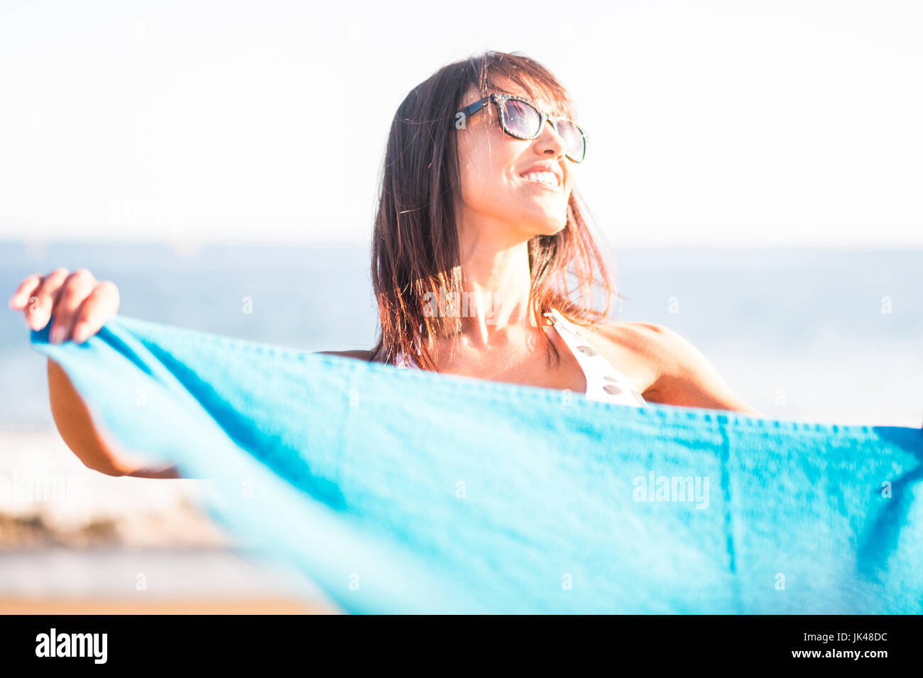 Caucasian woman holding blanket on beach Stock Photo