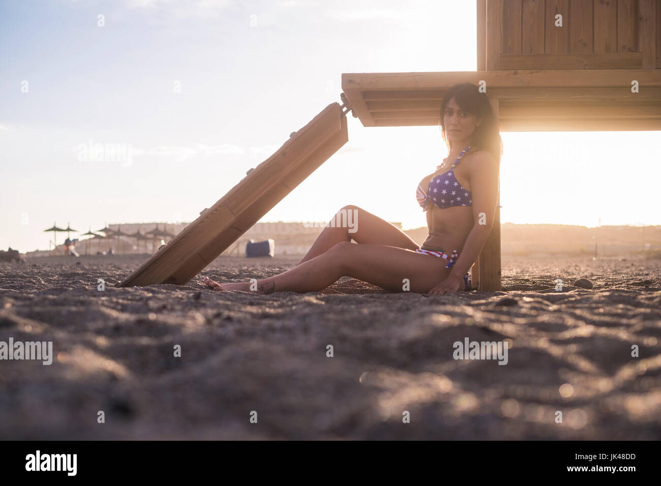 Caucasian woman sitting on beach leaning on cabana Stock Photo