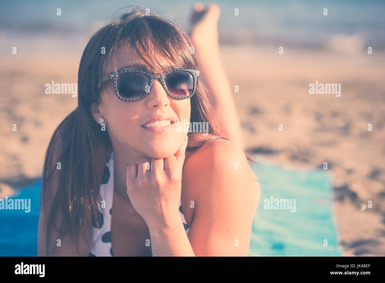 Caucasian woman laying on beach blanket Stock Photo