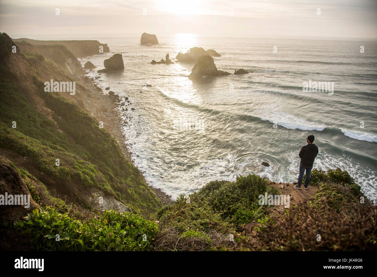 Caucasian man admiring scenic view of ocean sunset Stock Photo