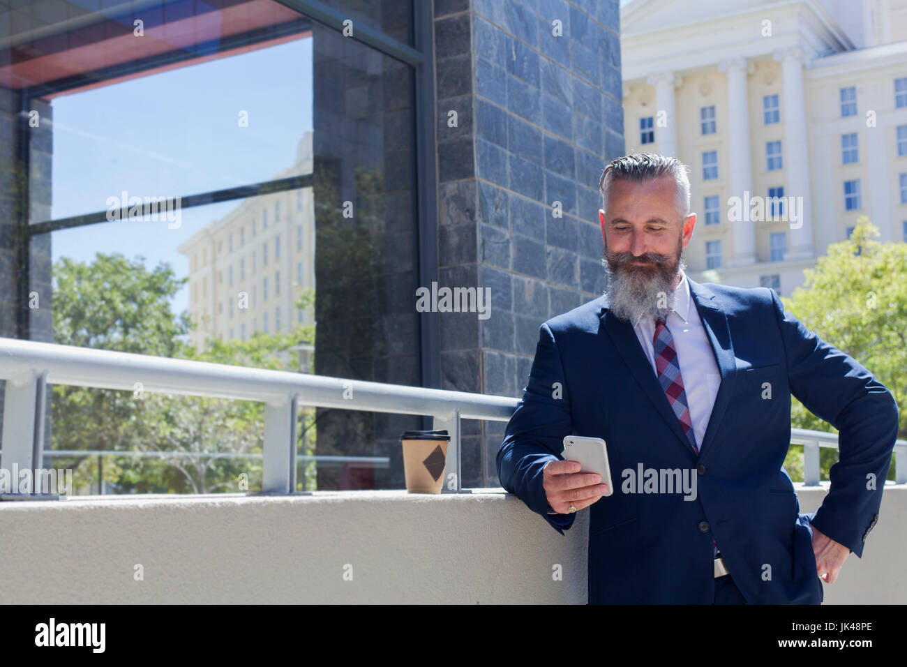Caucasian businessman texting on cell phone outdoors Stock Photo
