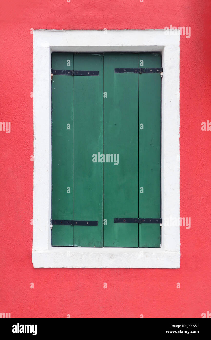 Closed green retro window shutters on red facade Stock Photo