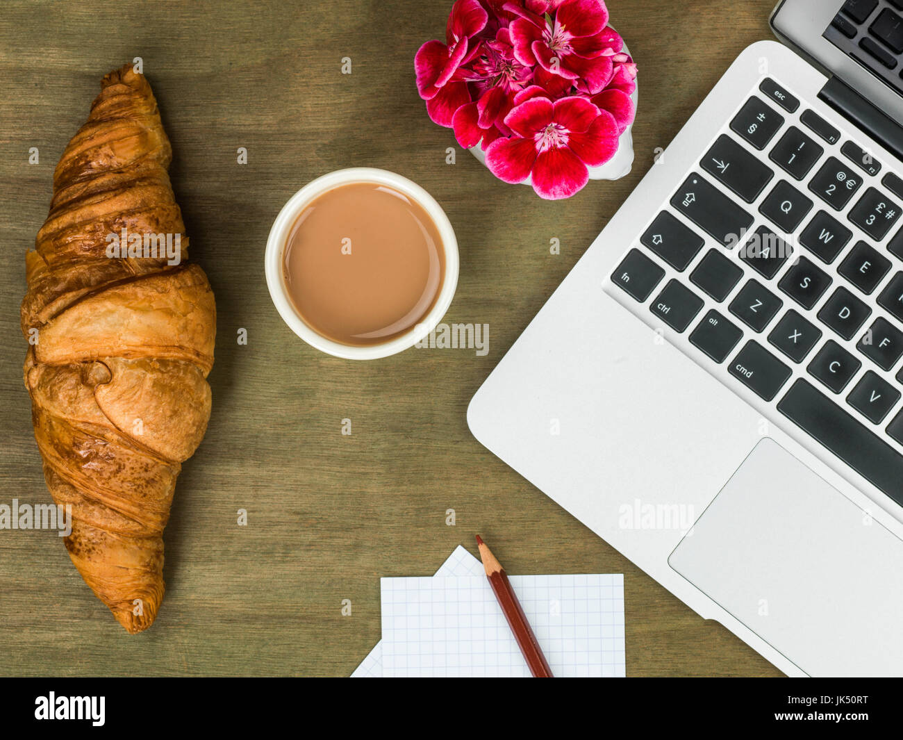 Croissant and a Cup of Tea Working Breakfast or Snack On A Wooden Distressed Desk Top Stock Photo