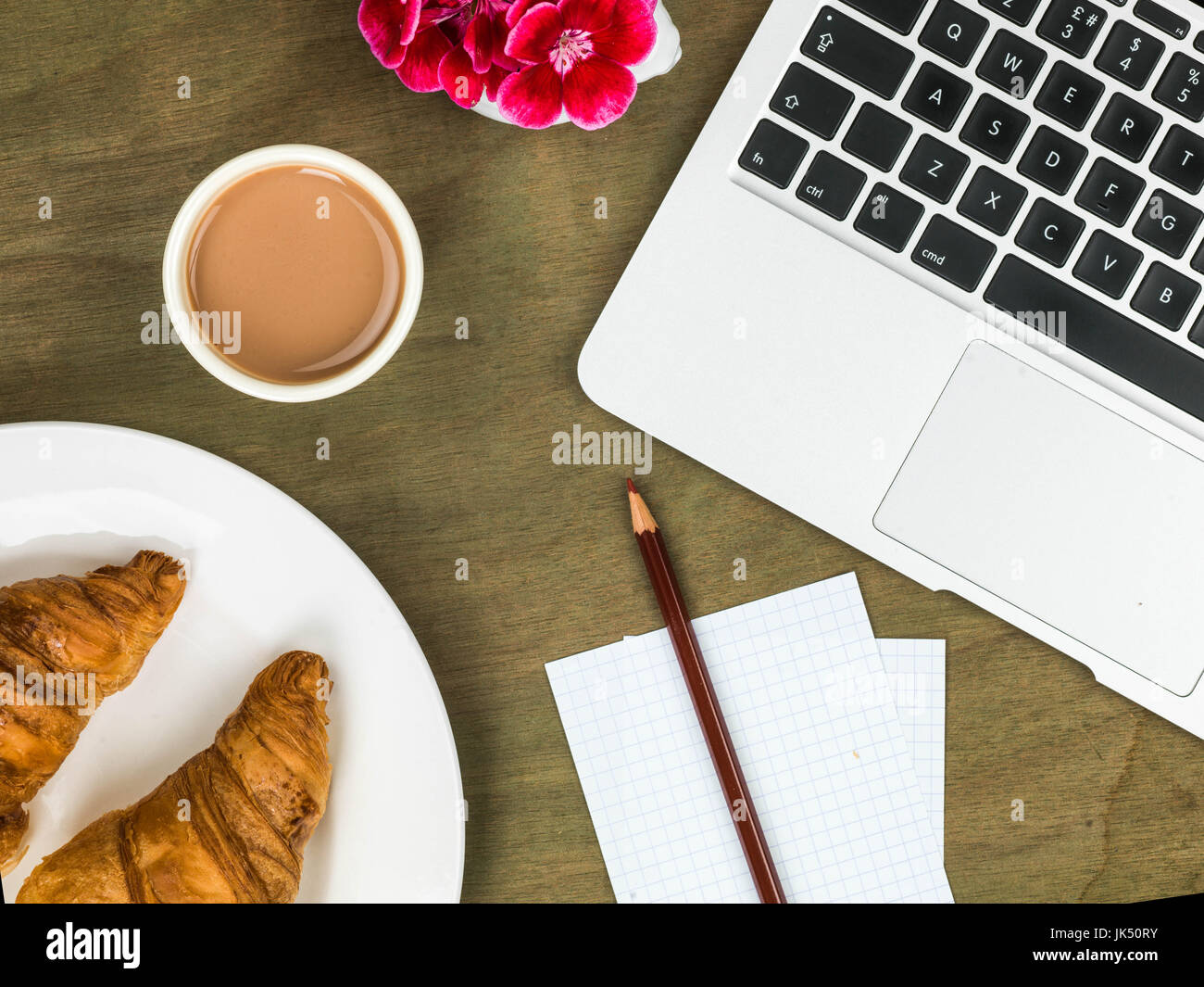 Croissant and a Cup of Tea Working Breakfast or Snack On A Wooden Distressed Desk Top Stock Photo
