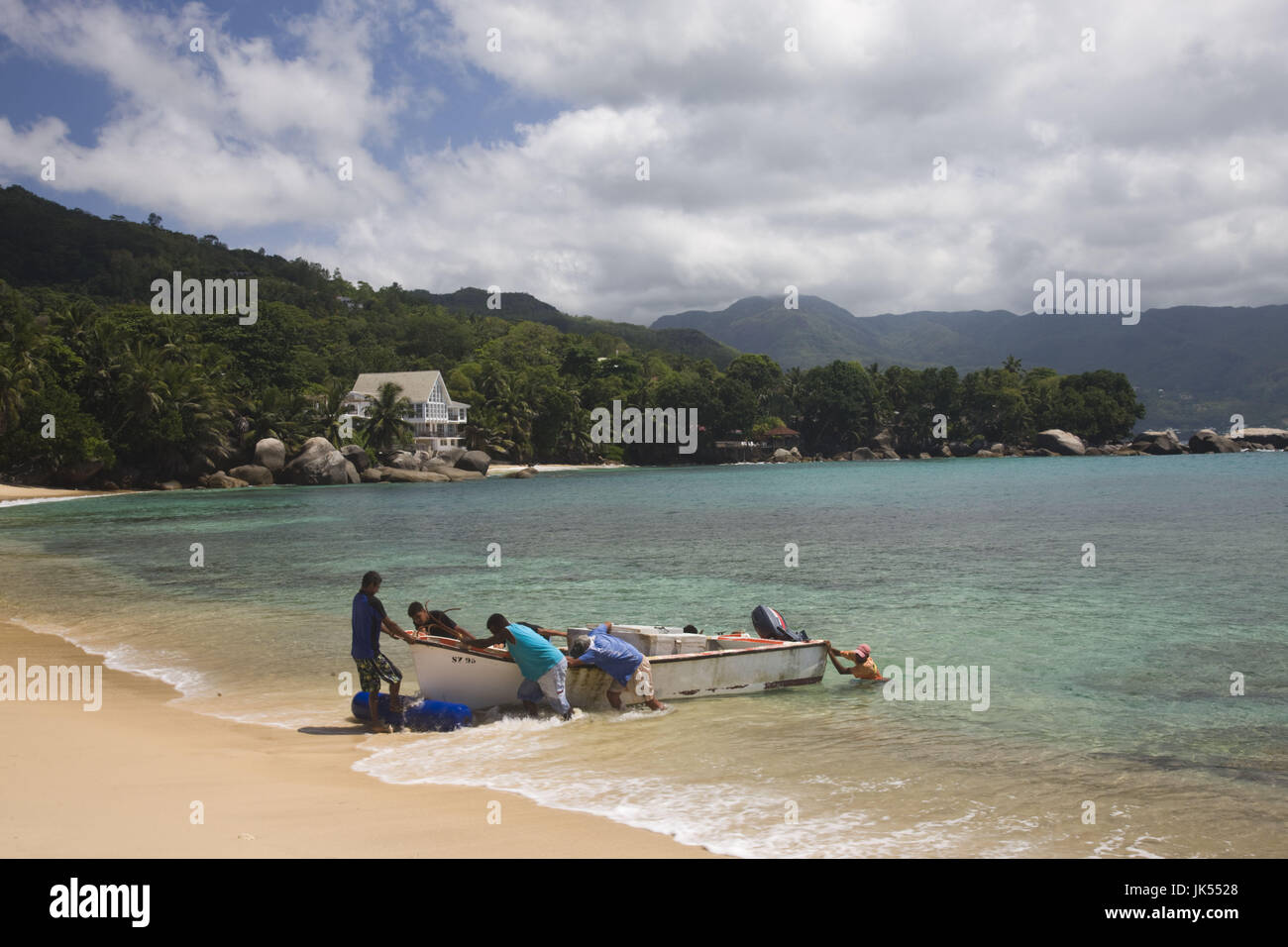 Seychelles, Mahe Island, Baie Beau Vallon, fishermen pulling boat on