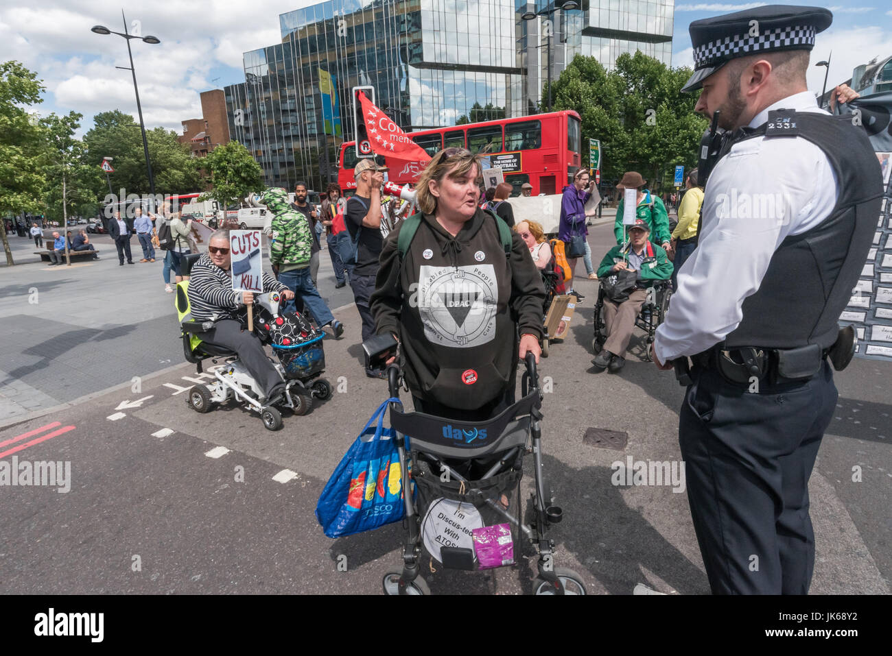 July 21, 2017 - London, UK - London, UK. 21st July 2017. A police officer talks to Paula Peters who says nothing to him as DPAC end their week of action during the London Para Athletics World Championships by blocking one carriageway of the Euston Road at Warren St for around ten minutes. The two police officers present asked them to move and then radioed for reinforcements, who arrived just after the protesters left the road. DPAC say that the government uses support of the para athletes as a cover for its campaign against the disabled which uses discredited tests to remove benefits and has r Stock Photo