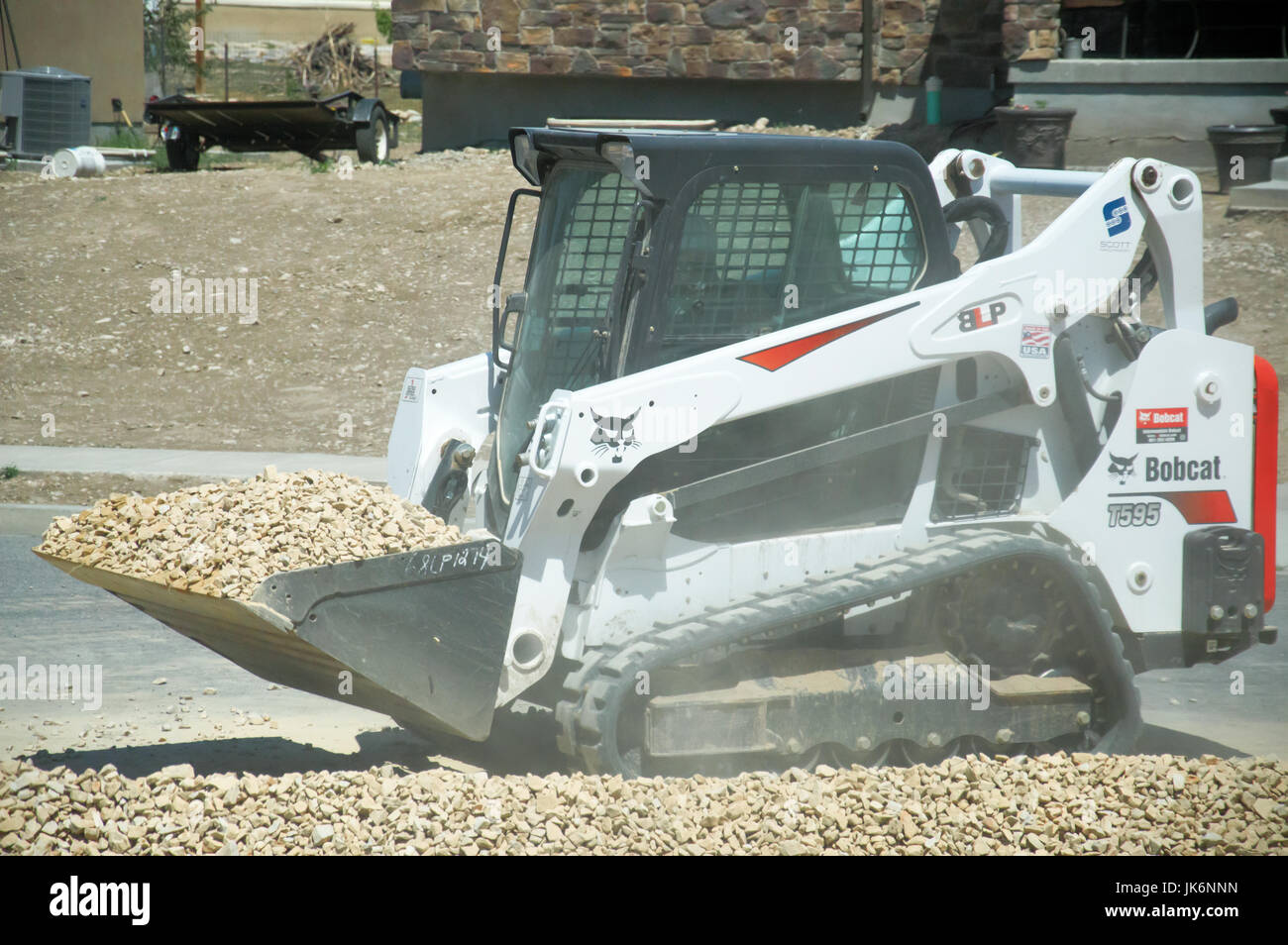 An small construction bobcat moving a pile of stones off the road. Stock Photo