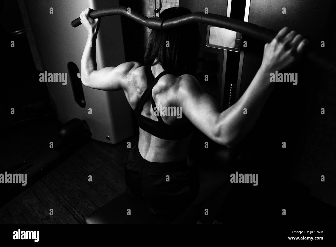 Woman Working Out Back In A Gym On Machine With Cable Stock Photo