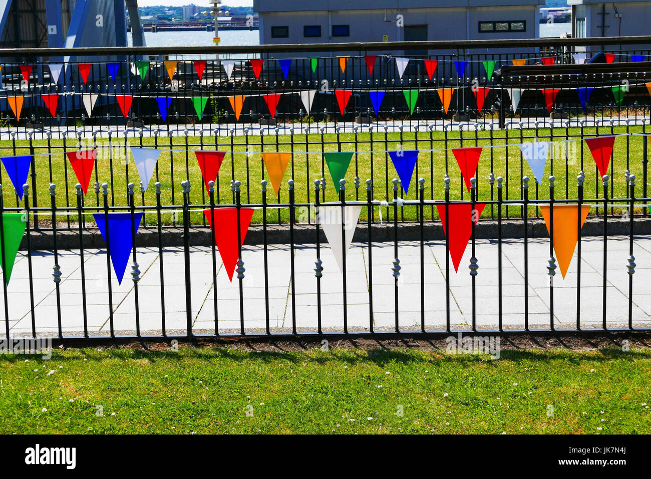 Colourful pendants hanging from ornate metal railing enclosed grassed