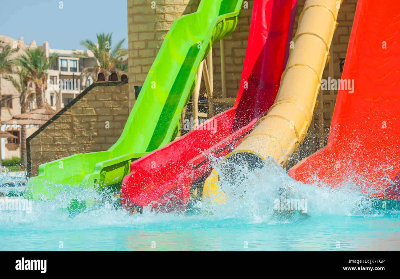 Water slides in aqua park at large outdoor swimming pool of luxury tropical resort hotel in summer Stock Photo