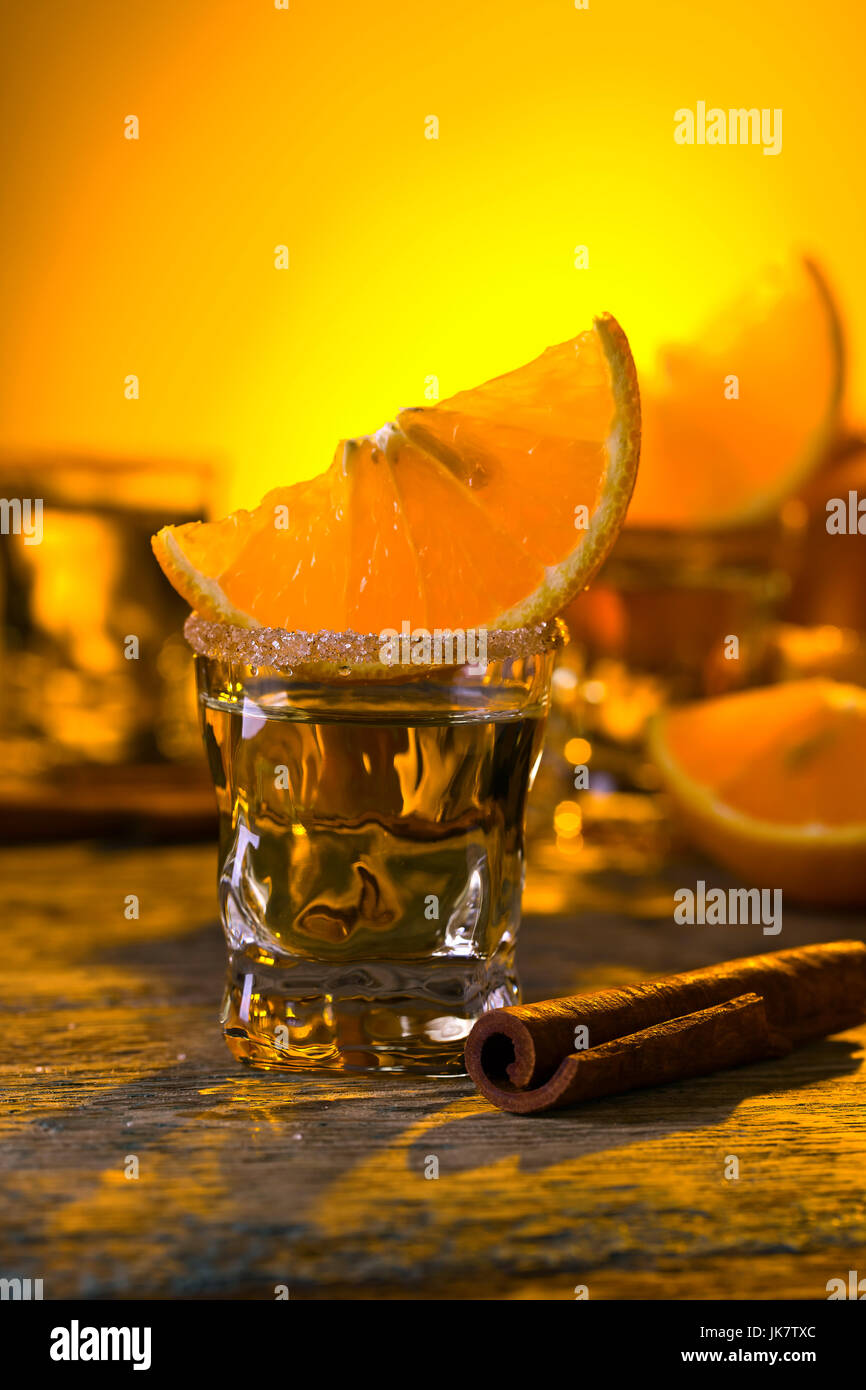 Gold tequila with orange and cinnamon on old wooden table Stock Photo