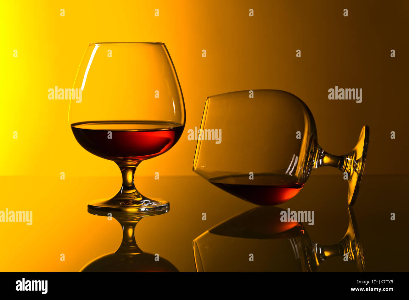Two snifters of brandy on a yellow background Stock Photo - Alamy