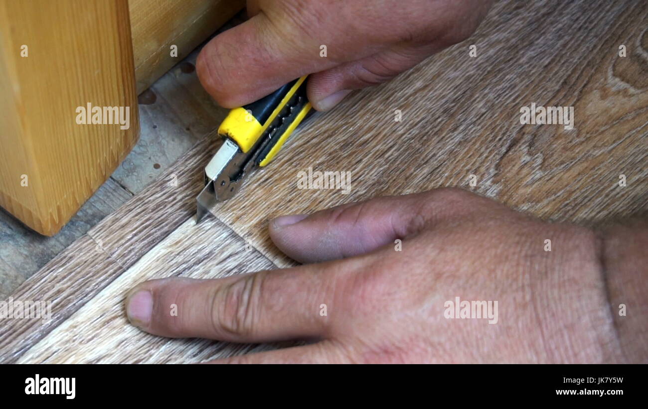 the worker cuts off the linoleum with a utility knife,fitting of