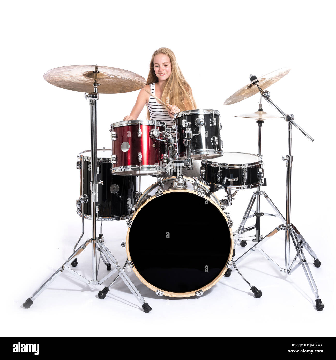 young blond caucasian teenage girl plays the drums in studio against white background Stock Photo