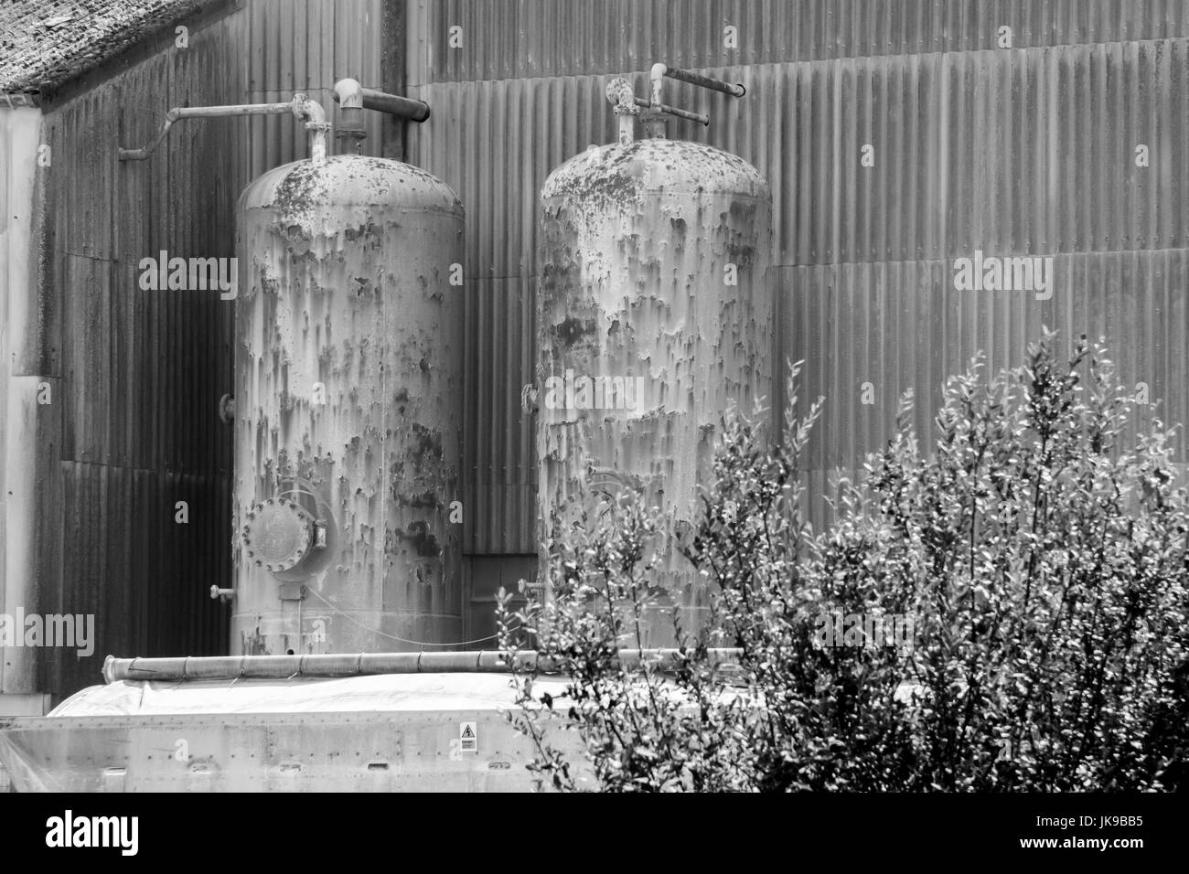 Black and white image of two external high pressure cylinders involved in a manufacturing process. Stock Photo