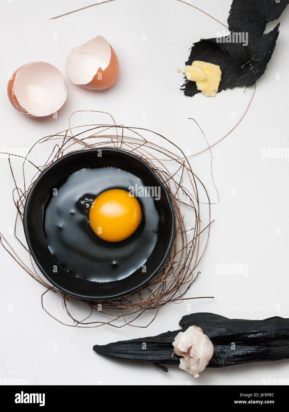 art of eggs on the black dish with the bush or Bird's nest and seasoning on white wooden background Stock Photo