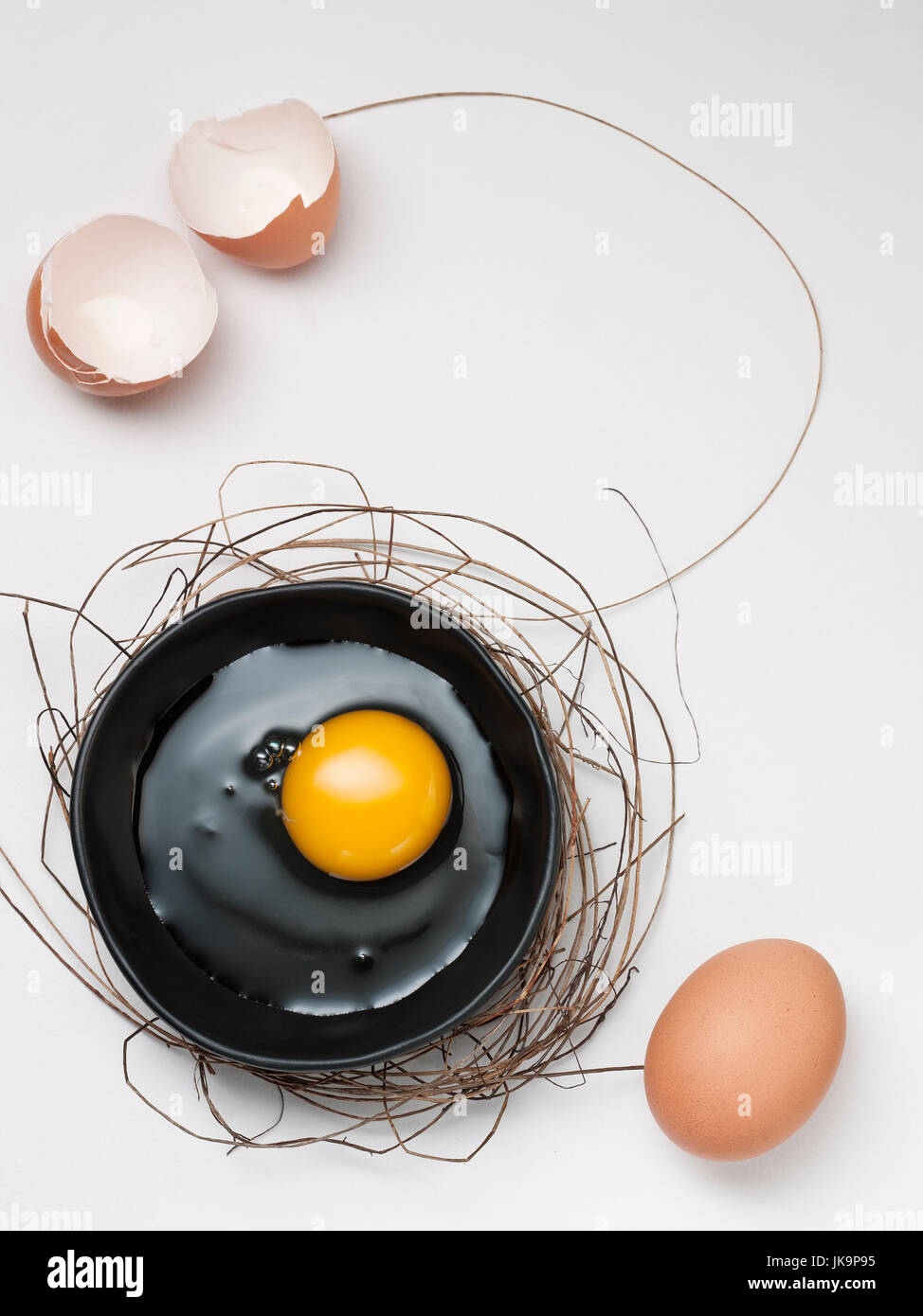 art of eggs on the black dish with the bush or Bird's nest and seasoning on white wooden background Stock Photo