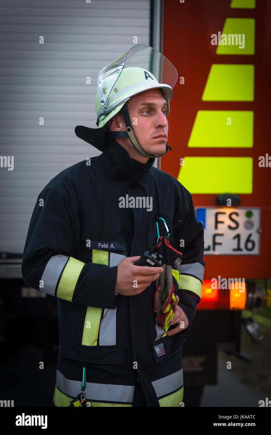 German fire fighter at fire truck observing column of fire at solstice celebrations and midsummer festival Stock Photo