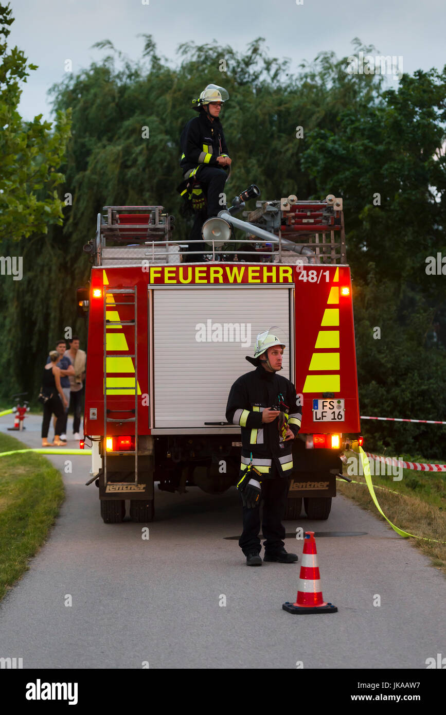 German fire fighter at fire truck observing column of fire at solstice celebrations and midsummer festival Stock Photo