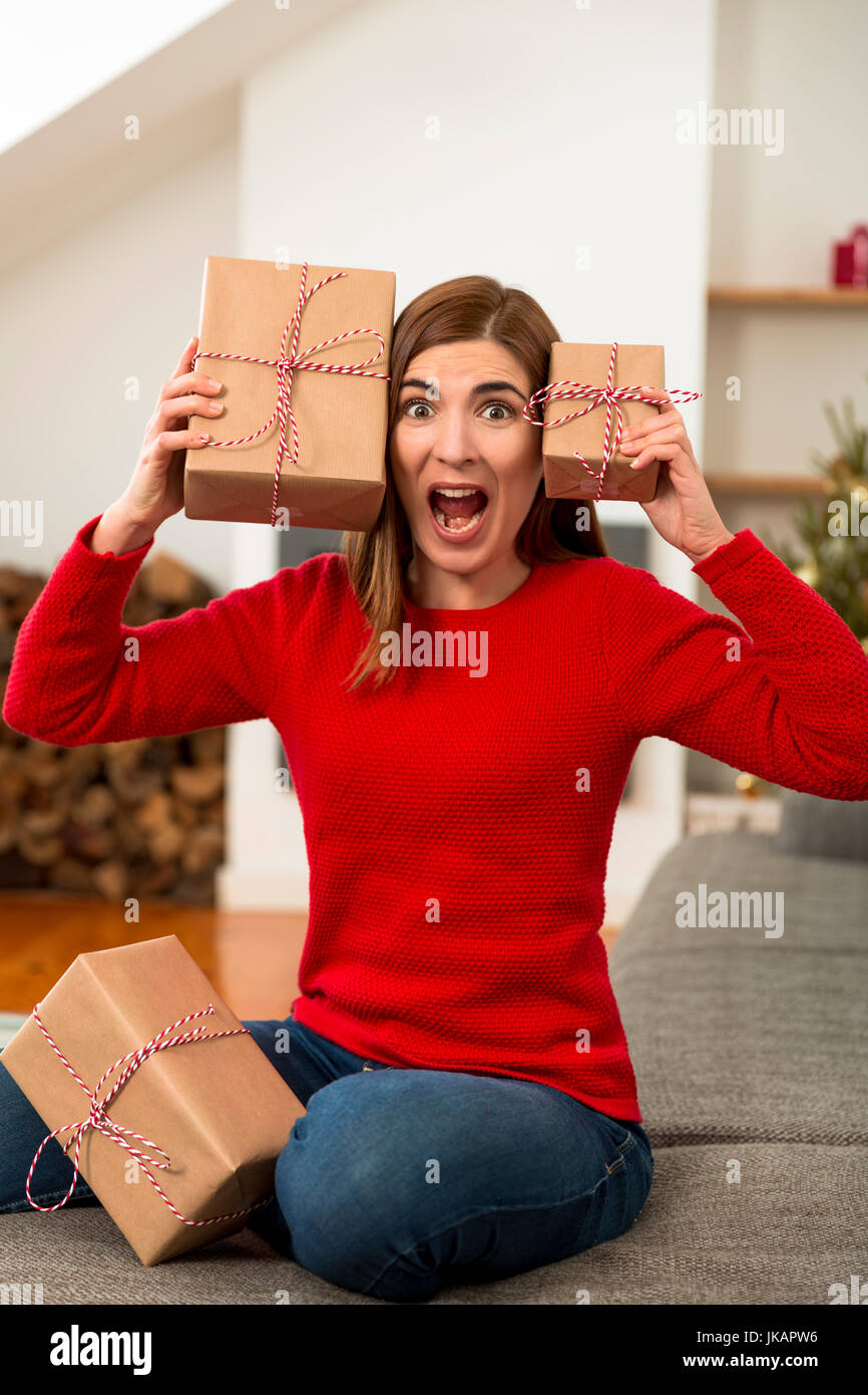 Beautiful woman at home in panic holding Christmas presents over her head Stock Photo