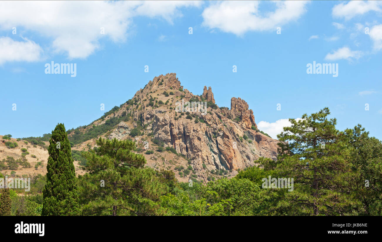 The mountain towering above the forest and the crowns of trees. The mountain range of Karagach, Crimea peninsula Stock Photo