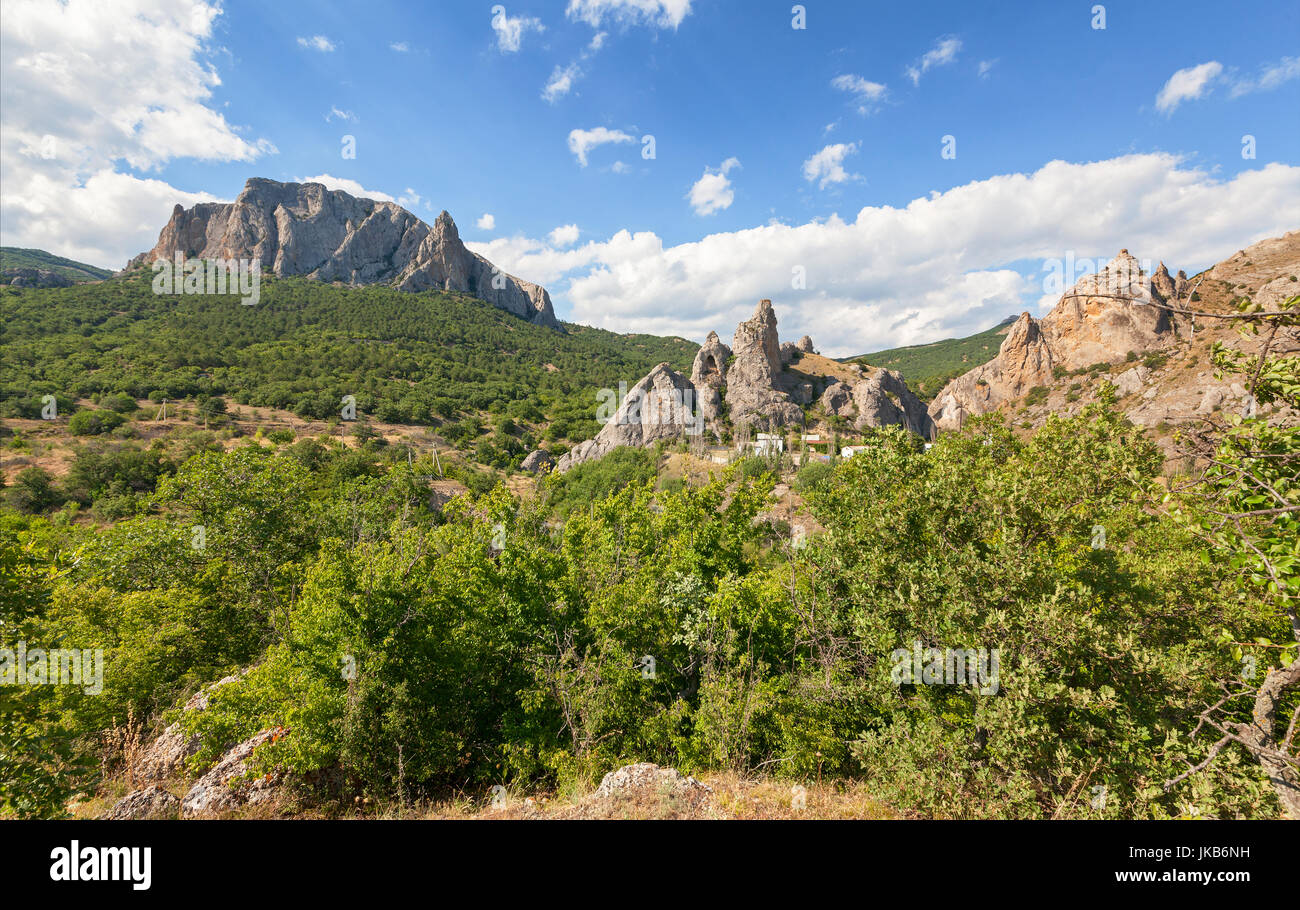Mountain valley with Parsuk-Kaya mountain towering over the forest and Delikli-Kaya rock against the sky with clouds. Mountains of the Crimean Peninsu Stock Photo