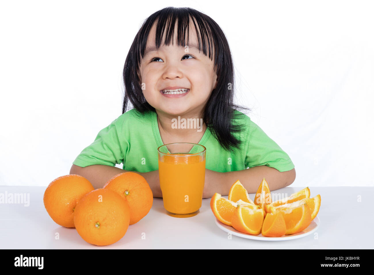 Happy Asian Chinese little girl drinking orange juice in isolated white ...