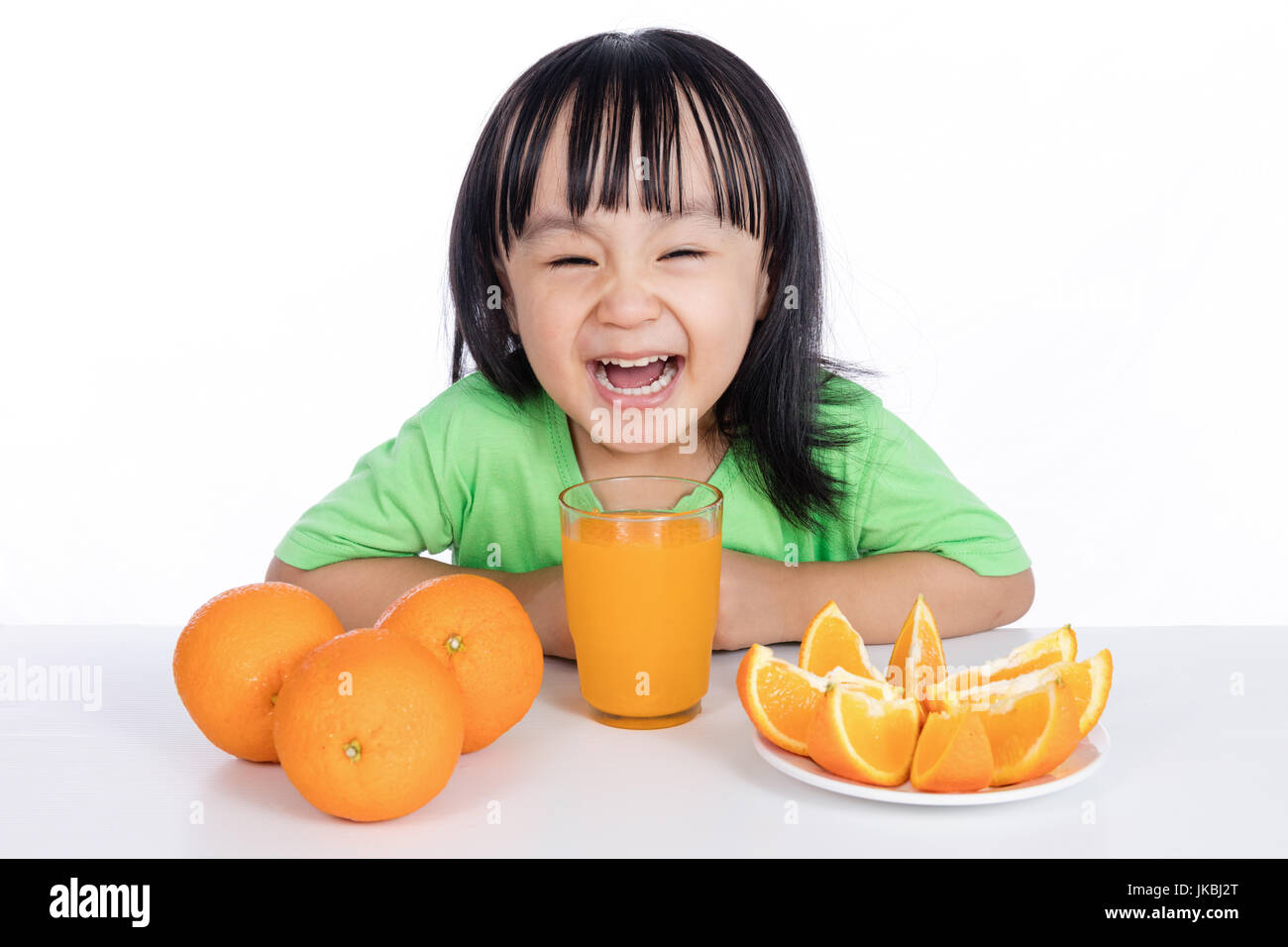 Happy Asian Chinese little girl drinking orange juice in isolated white ...
