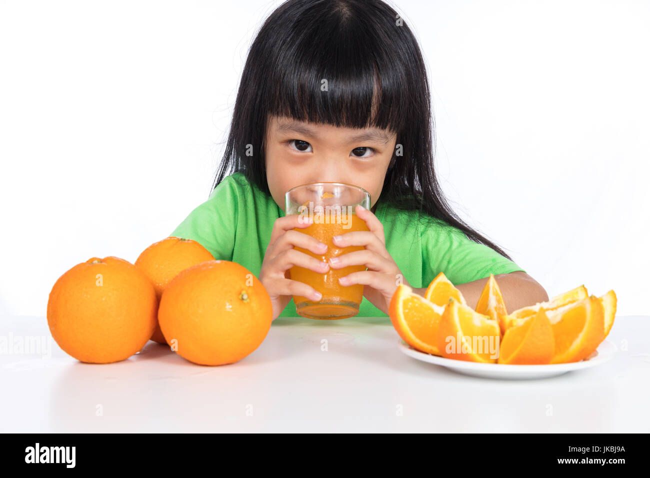 Happy Asian Chinese little girl drinking orange juice in isolated white ...