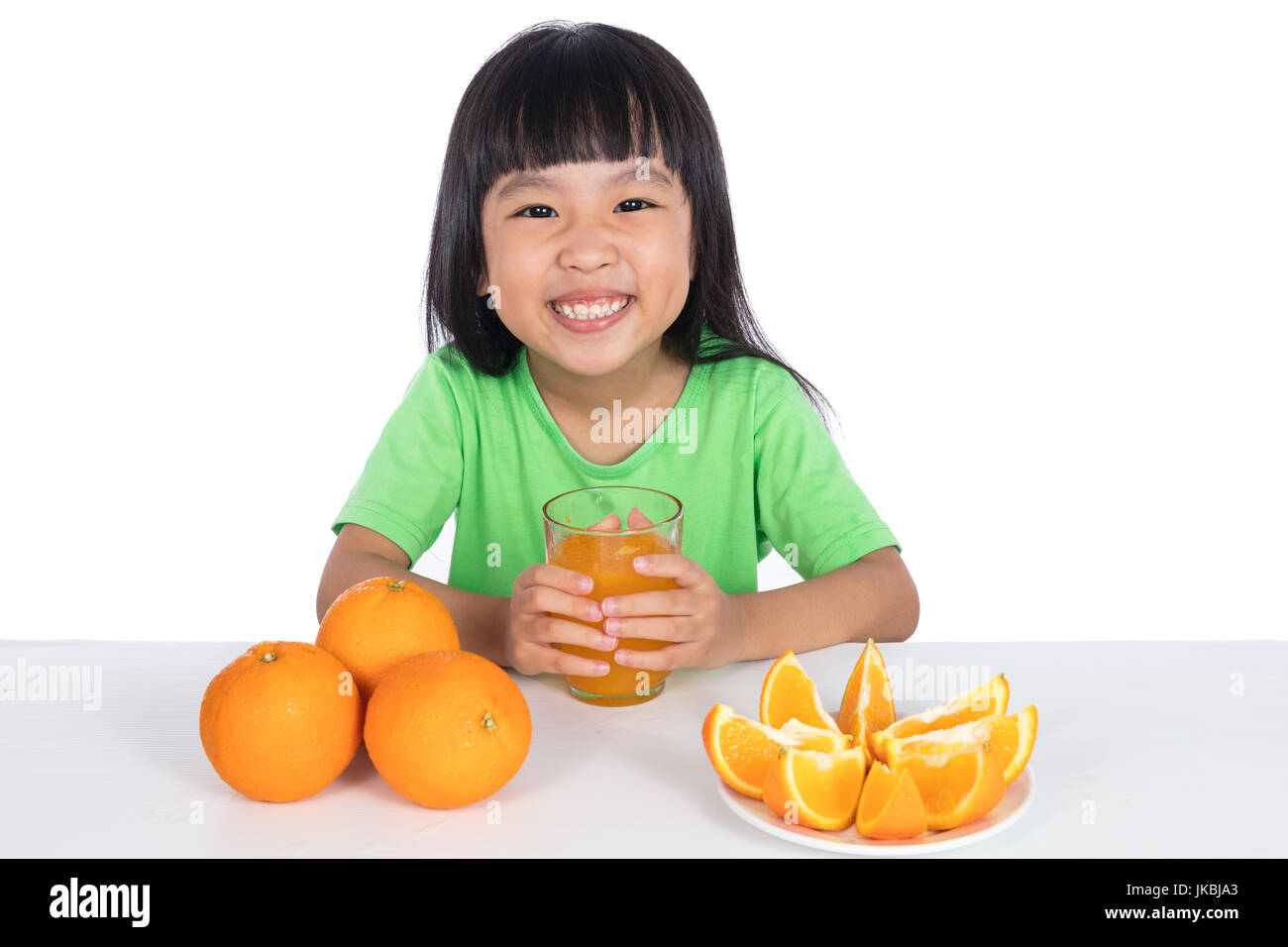 Happy Asian Chinese little girl drinking orange juice in isolated white ...