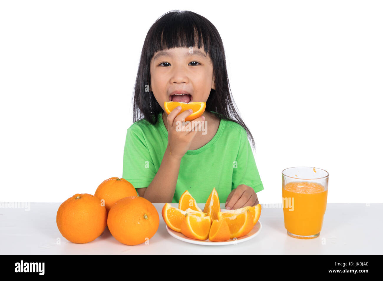 Happy Asian Chinese little girl eating orange in isolated white ...
