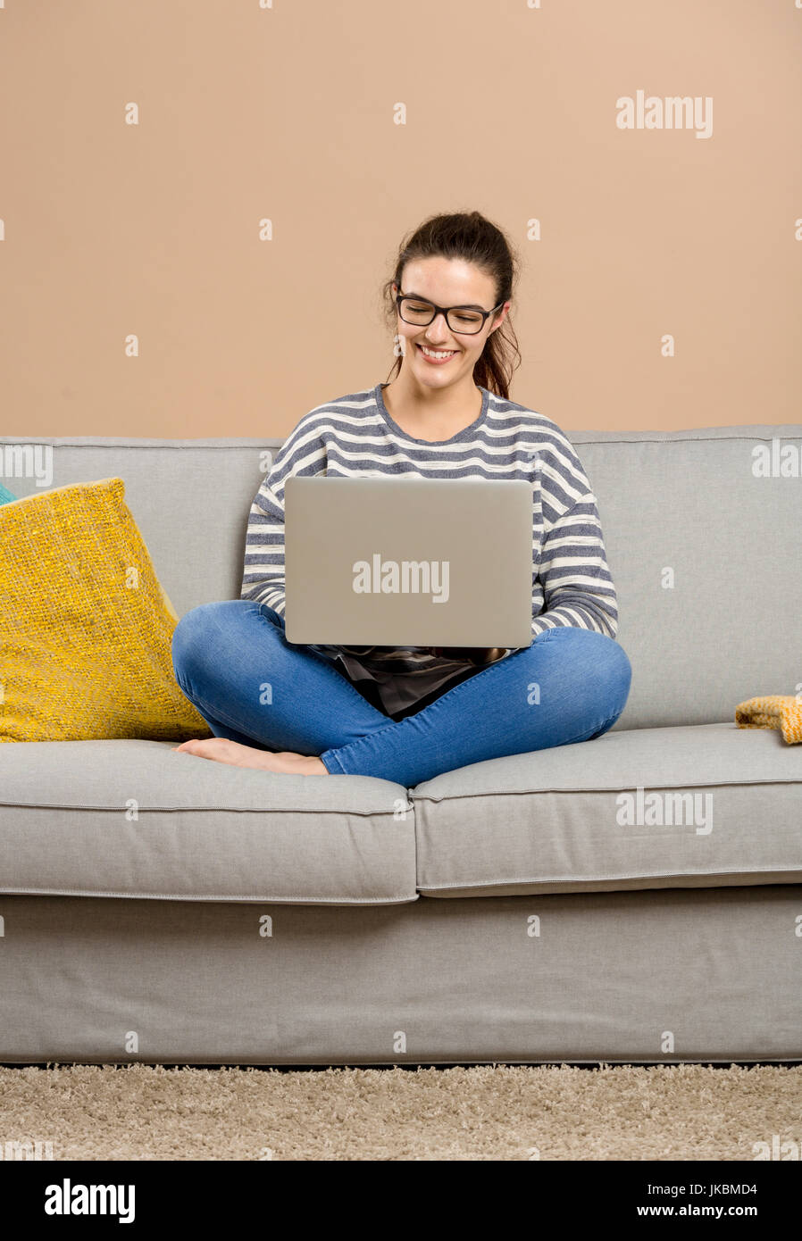 Beautiful woman at home sitting on the sofa and working with a laptop ...