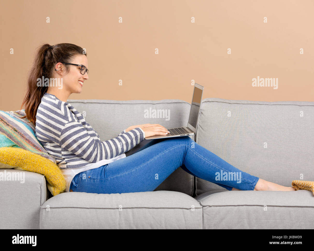 Beautiful woman at home sitting on the sofa and working with a laptop ...