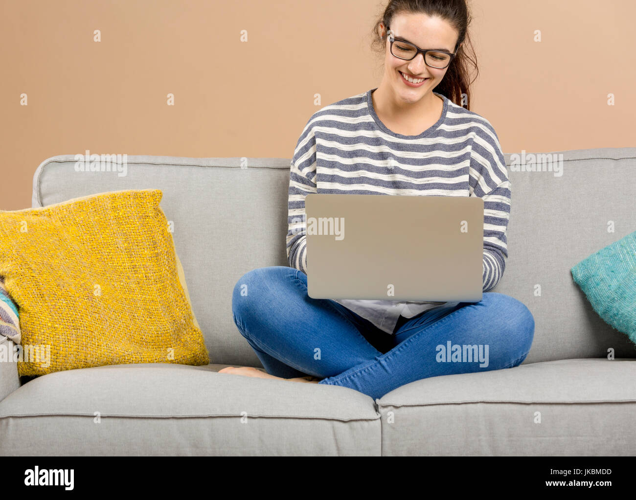 Beautiful woman at home sitting on the sofa and working with a laptop ...