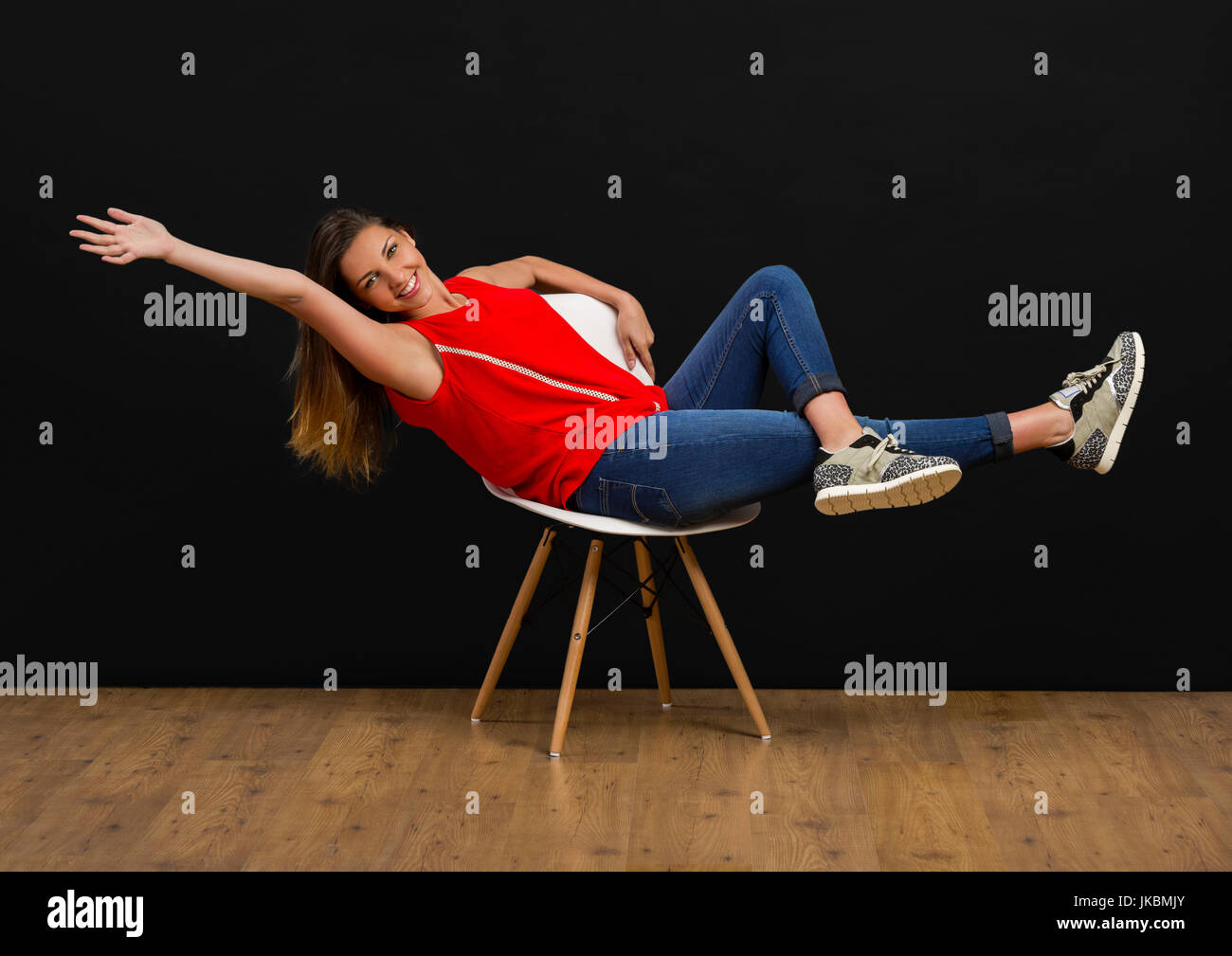 Beautiful young woman sitting on chair and smiling Stock Photo