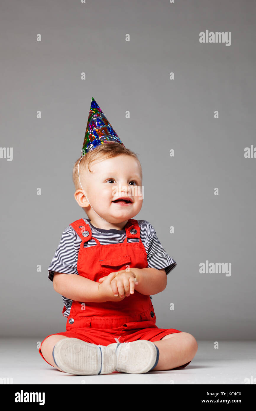 baby boy with birthday hat in overall red shorts Stock Photo Alamy