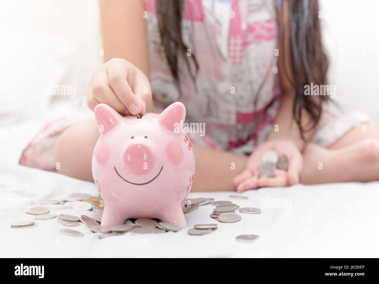 cute asian girl putting coin to piggy bank on bed, concept saving for ...