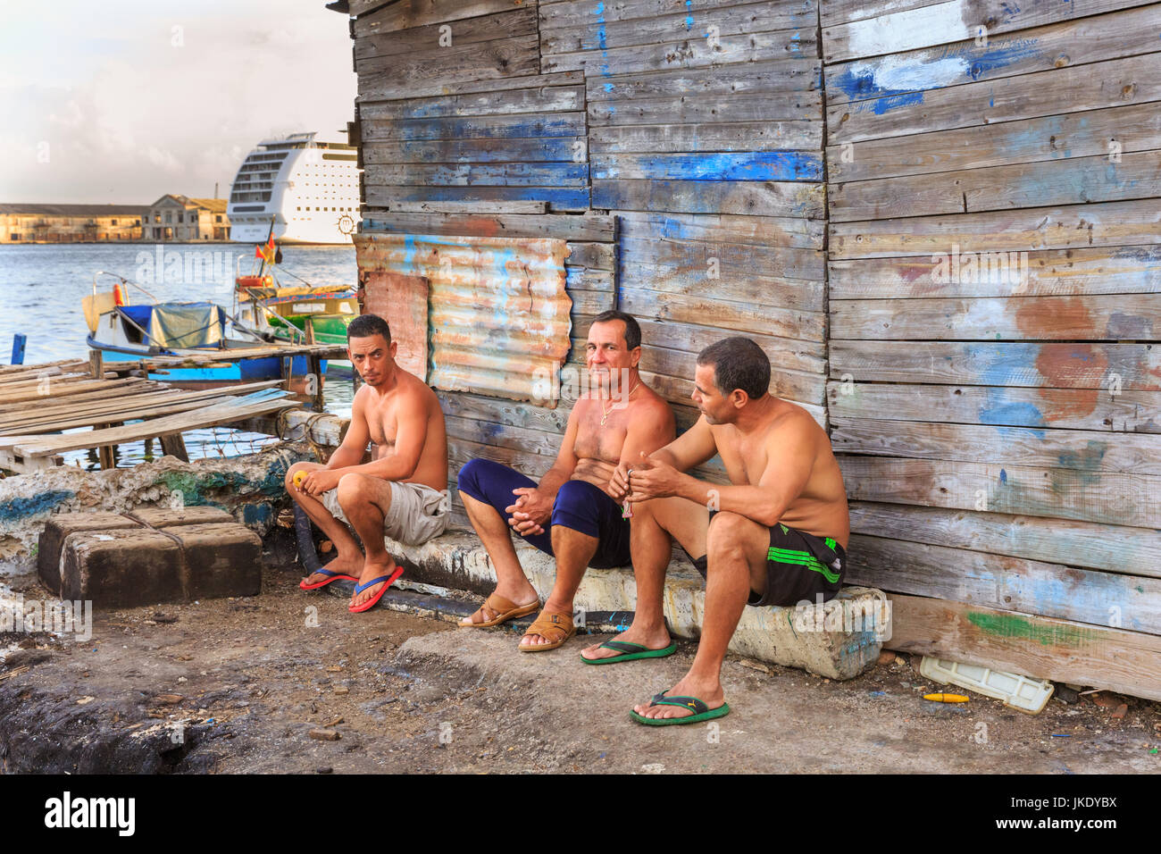 Fishermen rest against a shed in Casa Blanca, or Casablanca, urban fishing harbour, Havana, Cuba Stock Photo