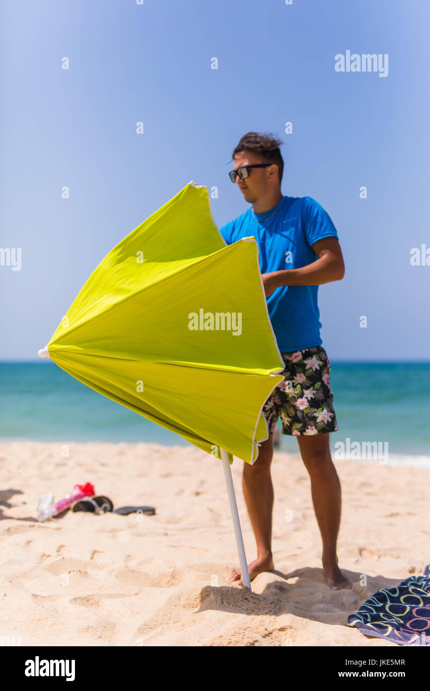 Young man install in sand solar umbrella on a beach Stock Photo Alamy