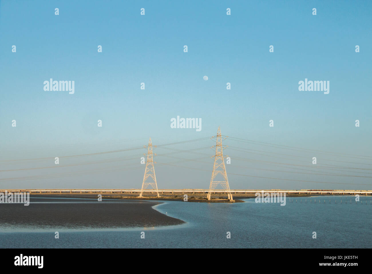 An evening on the highway , salt water area with electric poles and the moon Stock Photo