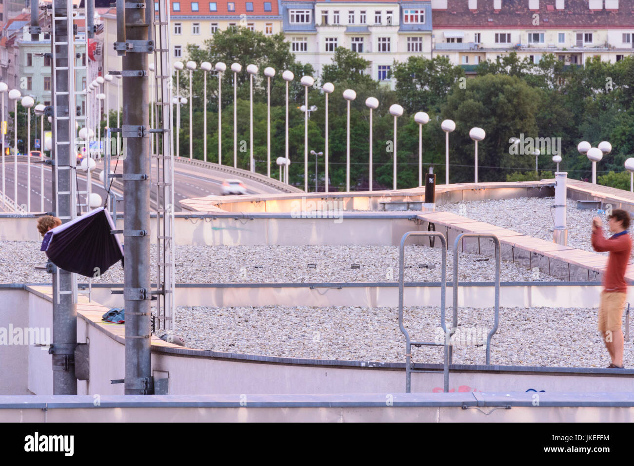 boy in hammock swinging between 2 phone masts, friend takes picture, roof top, illigal, Wien, Vienna, 22. Donaustadt, Wien, Austria Stock Photo