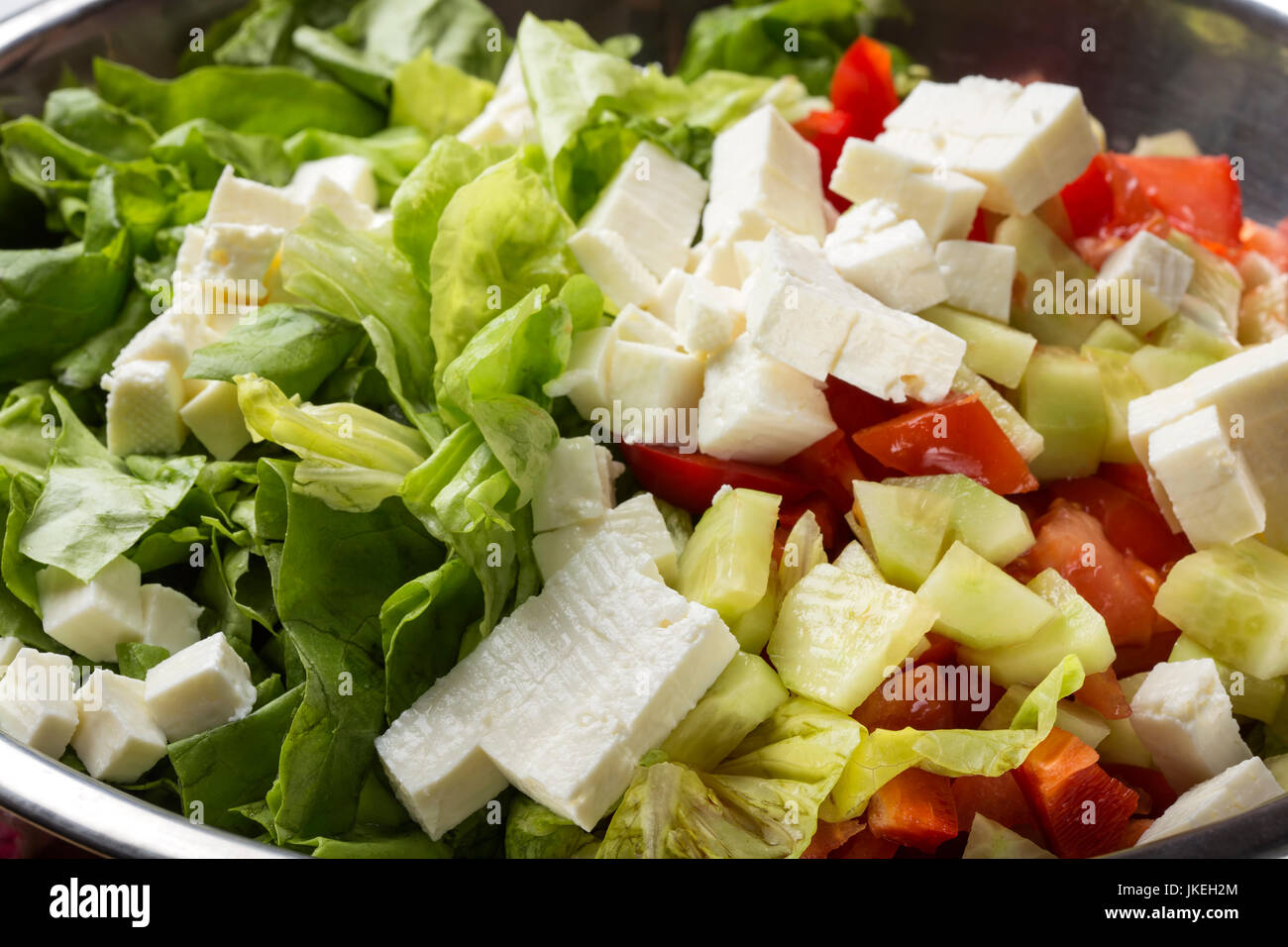 Fresh salad with cheese, tomatoes and cucumber in bowl Stock Photo