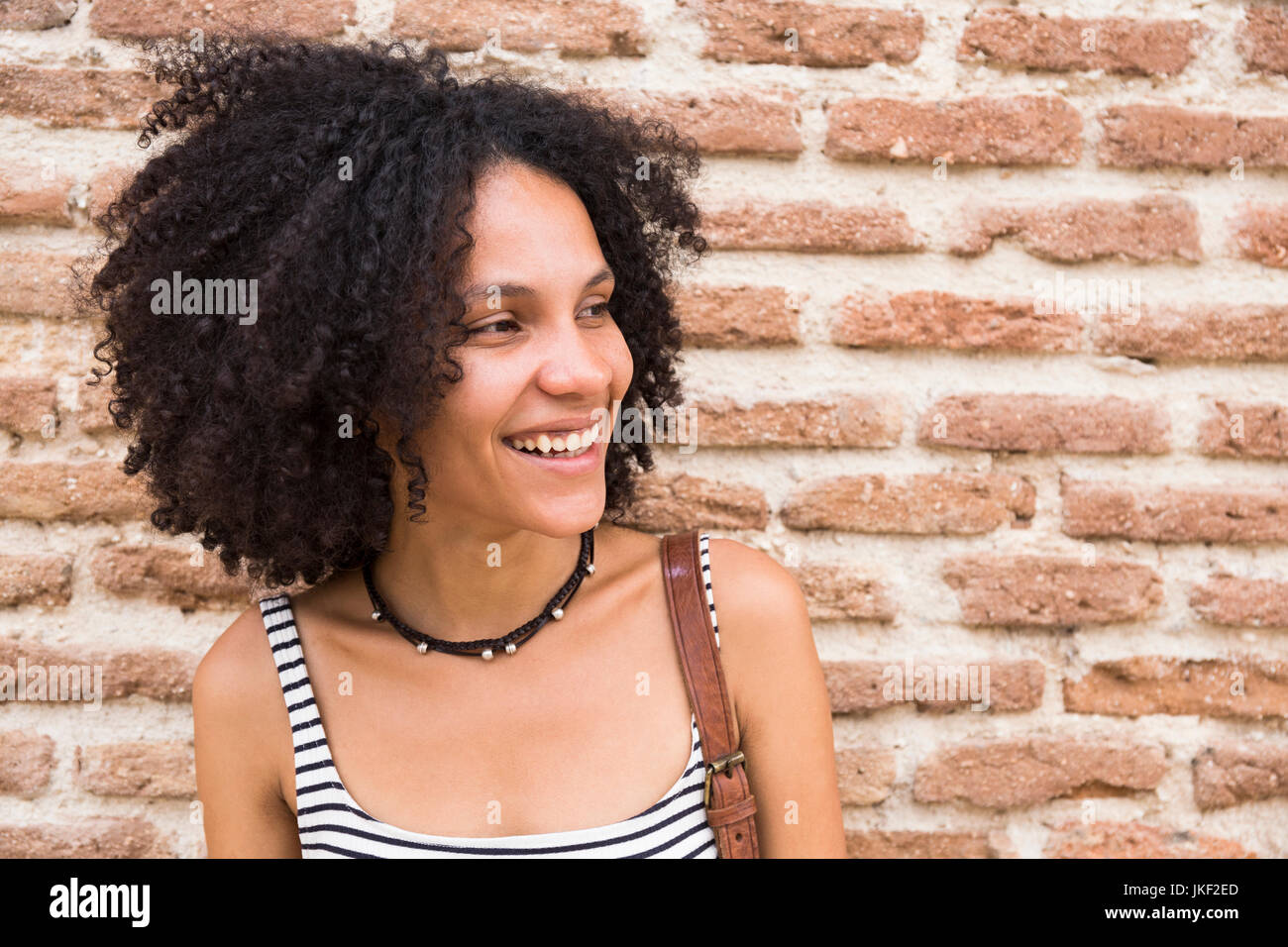 Portrait of smiling woman in front of brick wall Stock Photo - Alamy
