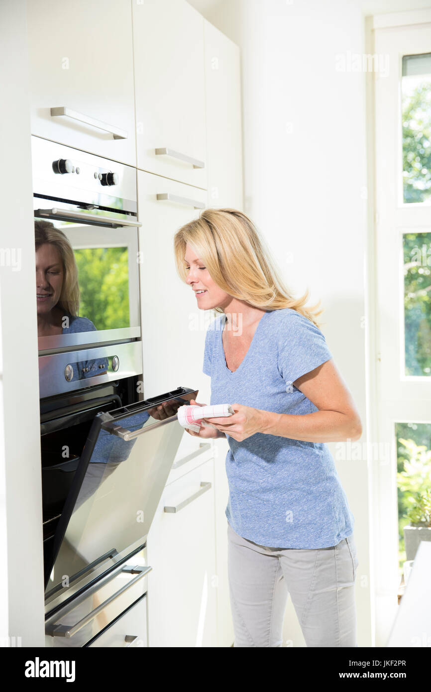 Woman in kitchen closing oven Stock Photo