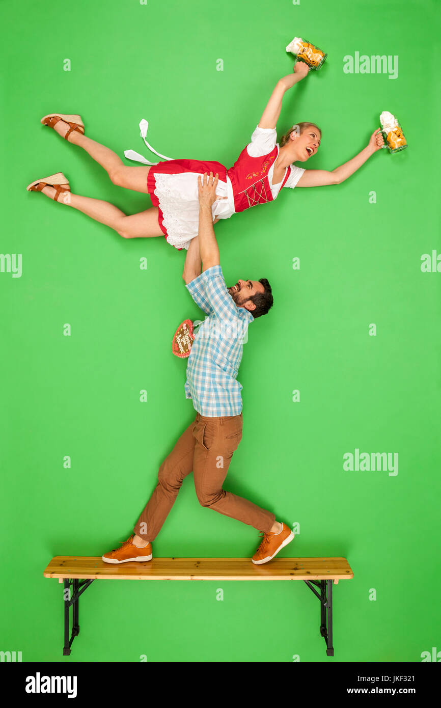 Man at the Oktoberfest lifting his partner, standing on a beer bench