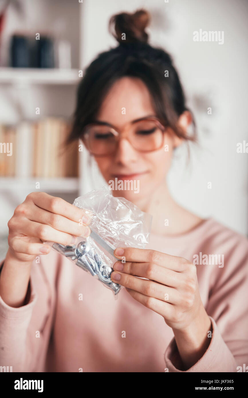 Woman looking at plastic bag with tools and screws for assembling furniture Stock Photo