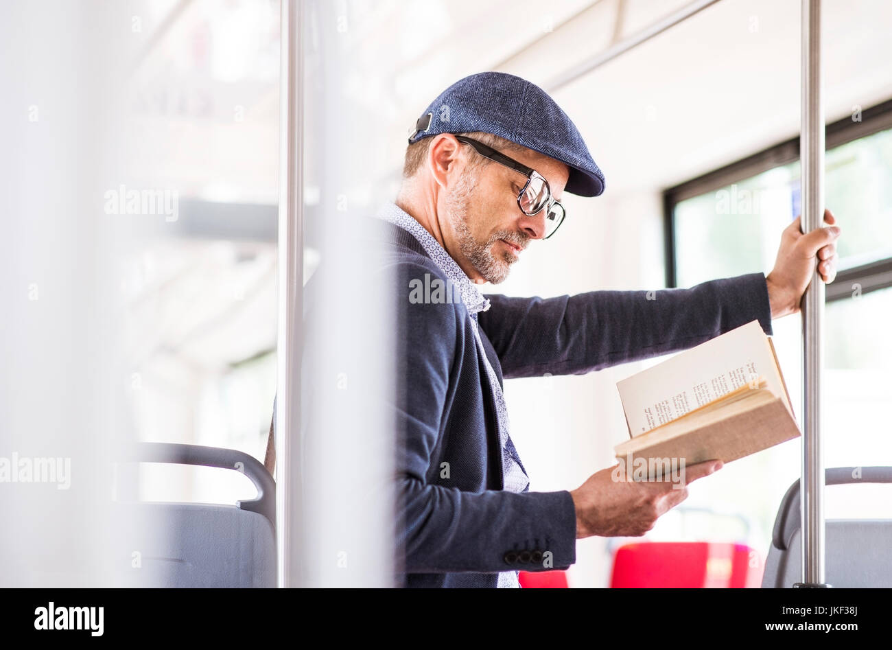 Man in bus reading book Stock Photo - Alamy